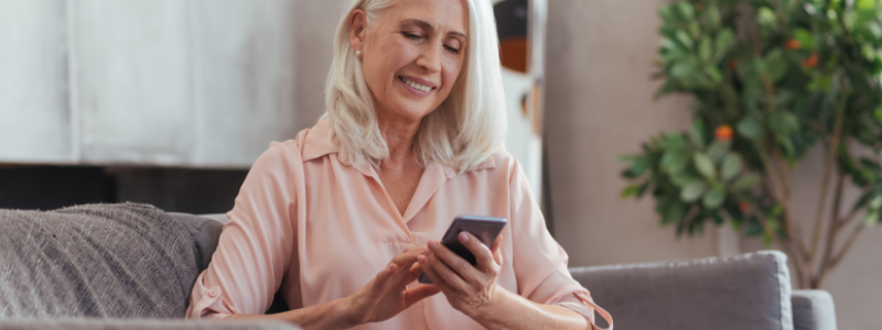 Elderly woman sitting on couch looking at phone